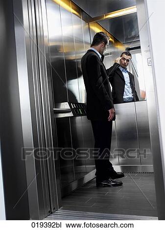 young businessman standing in elevator checking his looks in the mirror View Large Photo Image Stock Image - young businessman standing in elevator checking his looks in the mirror. Fotosearch