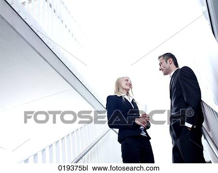 young businesswoman and man having conversation in office building View Large Photo Image Stock Image - young businesswoman and man having conversation in office building. Fotosearch