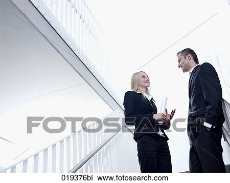 young businesswoman and man having conversation in office building View Large Photo Image Stock Image - young businesswoman and man having conversation in office building. Fotosearch