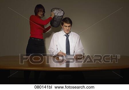 young businesswoman emptying wastebasket over her colleague View Large Photo Image Stock Image - young businesswoman emptying wastebasket over her colleague. Fotosearch
