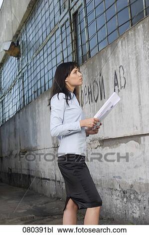 young businesswoman standing in front of factory building holding plan in hands View Large Photo Image Stock Image - young businesswoman standing in front of factory building holding plan in hands. Fotosearch