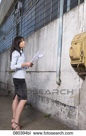 young businesswoman standing in front of factory building holding plan in hands View Large Photo Image Stock Image - young businesswoman standing in front of factory building holding plan in hands. Fotosearch