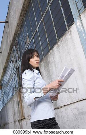 young businesswoman standing in front of factory building holding plan in hands View Large Photo Image Stock Image - young businesswoman standing in front of factory building holding plan in hands. Fotosearch