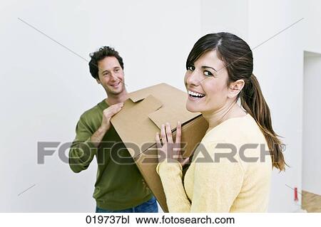 young couple carrying moving boxes into their new home View Large Photo Image Stock Image - young couple carrying moving boxes into their new home. Fotosearch