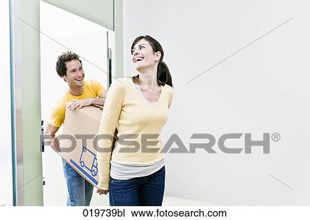 Stock Image - young couple carrying moving boxes into their new home. Fotosearch