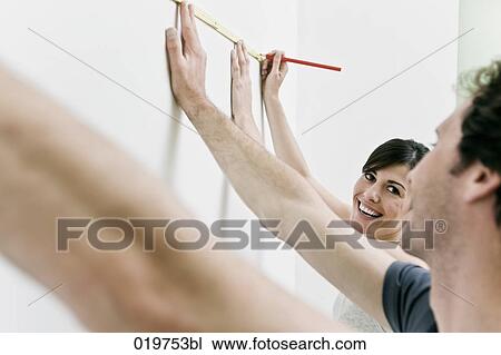 young couple making marking on the wall with folding rule and pencil View Large Photo Image Stock Image - young couple making marking on the wall with folding rule and pencil. Fotosearch