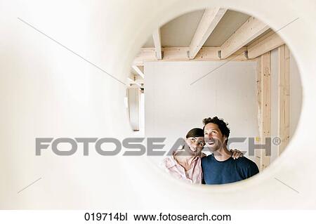 young couple on construction site of their new home seen through hole in wall View Large Photo Image Stock Image - young couple on construction site of their new home seen through hole in wall. Fotosearch
