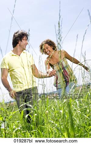 young couple walking hand in hand through meadow View Large Photo Image Stock Image - young couple walking hand in hand through meadow. Fotosearch
