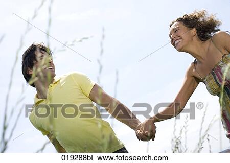 young couple walking hand in hand through meadow View Large Photo Image Stock Image - young couple walking hand in hand through meadow. Fotosearch