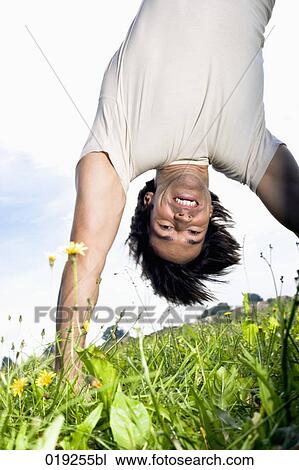 young man doing handstand on grass View Large Photo Image Stock Image - young man doing handstand on grass. Fotosearch