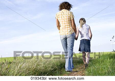 young mother and daughter walking hand in hand on path in the countryside View Large Photo Image Stock Image - young mother and daughter walking hand in hand on path in the countryside. Fotosearch