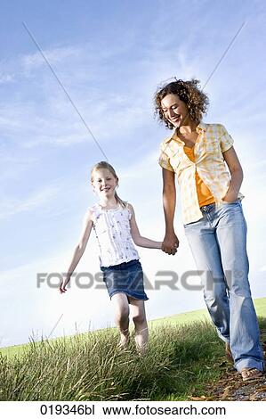 young mother and daughter walking hand in hand on path in the countryside View Large Photo Image Stock Image - young mother and daughter walking hand in hand on path in the countryside. Fotosearch