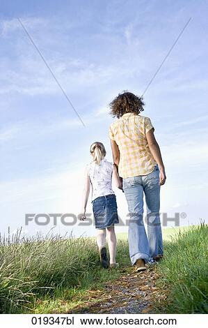 young mother and daughter walking hand in hand on path in the countryside View Large Photo Image Stock Image - young mother and daughter walking hand in hand on path in the countryside. Fotosearch