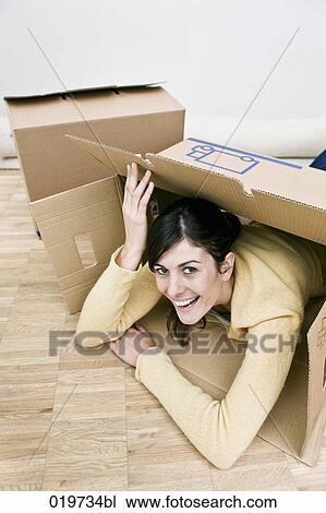 young woman lying on floor peeking through moving box View Large Photo Image Stock Image - young woman lying on floor peeking through moving box. Fotosearch