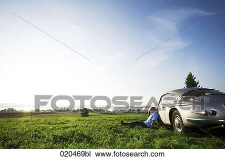 bald man sitting on meadow by his classic car watching landscape View Large Photo Image Stock Image - bald man sitting on meadow by his classic car watching landscape. Fotosearch