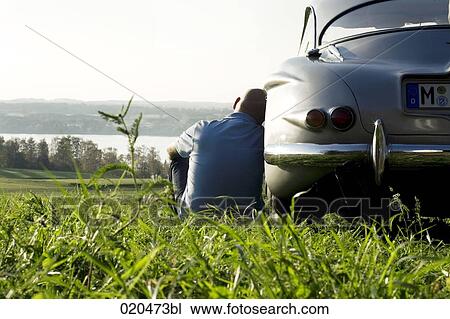 bald man sitting on meadow by his classic car watching landscape View Large Photo Image Stock Image - bald man sitting on meadow by his classic car watching landscape. Fotosearch