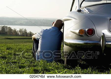 bald man sitting on meadow by his classic car watching landscape View Large Photo Image Stock Image - bald man sitting on meadow by his classic car watching landscape. Fotosearch