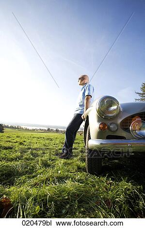 bald man standing on meadow by his classic car watching landscape View Large Photo Image Stock Image - bald man standing on meadow by his classic car watching landscape. Fotosearch