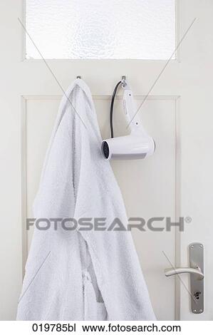 Stock Image - bathrobe and hair dryer hanging on bathroom door. Fotosearch