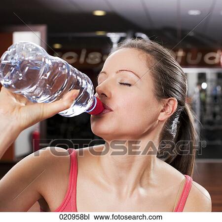 headshot of young drinking water from plastic bottle in gym View Large Photo Image Stock Image - headshot of young drinking water from plastic bottle in gym. Fotosearch