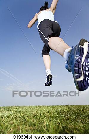 low angle view of young woman jogging through park View Large Photo Image Stock Image - low angle view of young woman jogging through park. Fotosearch