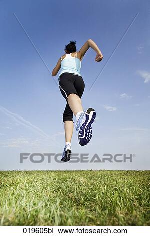 low angle view of young woman jogging through park View Large Photo Image Stock Image - low angle view of young woman jogging through park. Fotosearch