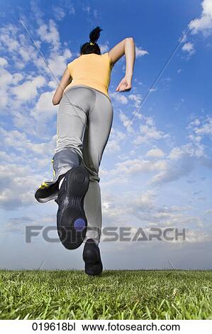 low angle view of young woman jogging through park View Large Photo Image Stock Image - low angle view of young woman jogging through park. Fotosearch