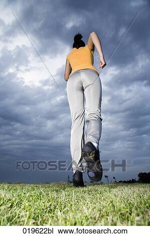 low angle view of young woman jogging through park View Large Photo Image Stock Image - low angle view of young woman jogging through park. Fotosearch