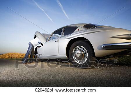 man repairing his classic car on empty road View Large Photo Image Stock Image - man repairing his classic car on empty road. Fotosearch