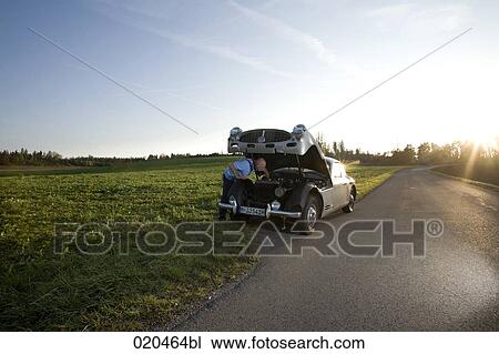 man repairing his classic car on empty road View Large Photo Image Stock Image - man repairing his classic car on empty road. Fotosearch
