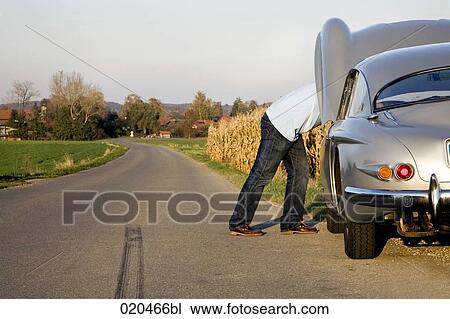 man repairing his classic car on empty road View Large Photo Image Stock Image - man repairing his classic car on empty road. Fotosearch