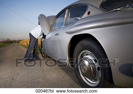 man repairing his classic car on empty road View Large Photo Image Stock Image - man repairing his classic car on empty road. Fotosearch