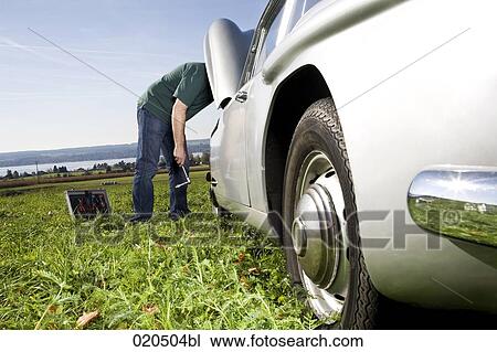 man repairing his classic car on meadow View Large Photo Image Stock Image - man repairing his classic car on meadow. Fotosearch