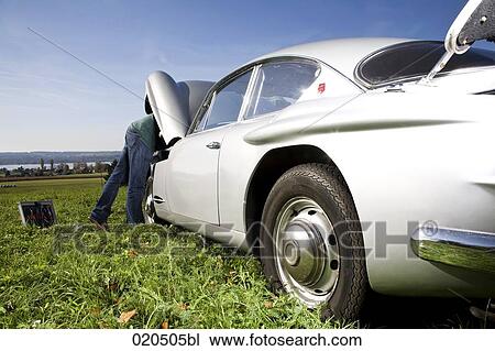 man repairing his classic car on meadow View Large Photo Image Stock Image - man repairing his classic car on meadow. Fotosearch