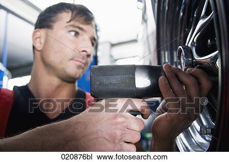 Stock Image - mechanic changing tire on car. Fotosearch
