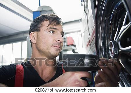 mechanic changing tire on car View Large Photo Image Stock Image - mechanic changing tire on car. Fotosearch