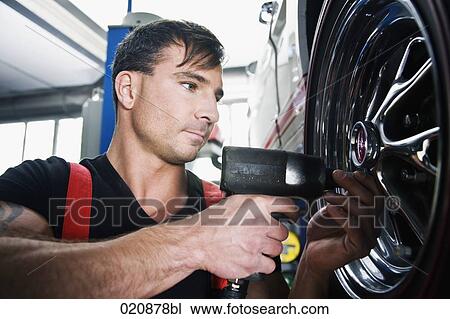 Stock Image - mechanic changing tire on car. Fotosearch
