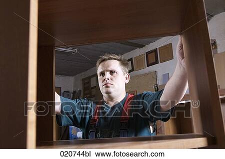 Stock Image - portrait of craftsman assembling furniture in workshop. Fotosearch