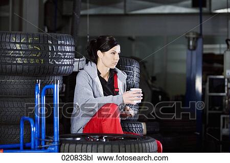 Stock Image - portrait of female mechanic having coffee break in garage. Fotosearch