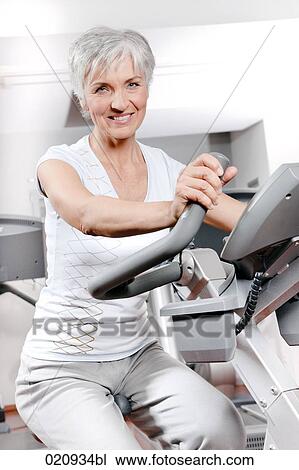 portrait of mature woman on exercise bike at gym View Large Photo Image Stock Image - portrait of mature woman on exercise bike at gym. Fotosearch