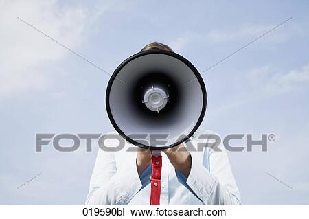 Stock Image - portrait of young businesswoman hidden behind megaphone. Fotosearch