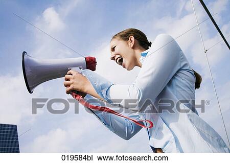 Stock Image - portrait of young businesswoman shouting through megaphone. Fotosearch