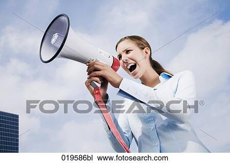 Stock Image - portrait of young businesswoman shouting through megaphone. Fotosearch