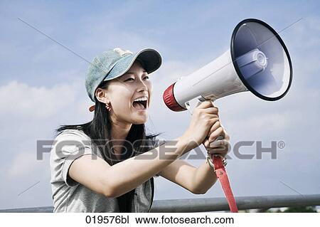 Stock Image - portrait of young japanese woman shouting through megaphone. Fotosearch