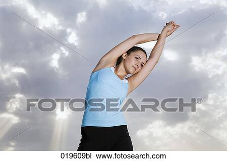 Stock Image - portrait of young jogger doing stretching exercises in park. Fotosearch