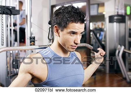 Stock Image - portrait of young man exercising with weight machine. Fotosearch