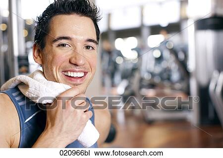 Stock Image - portrait of young man taking a rest in gym. Fotosearch