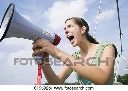 Stock Image - portrait of young woman shouting through megaphone. Fotosearch