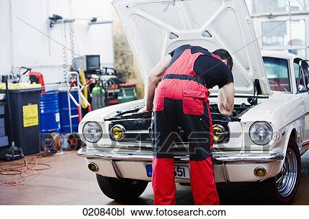 Stock Image - rear view of mechanic repairing car engine. Fotosearch