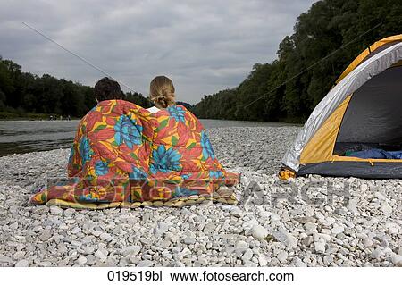 rear view of young couple sitting on riverbank near tent View Large Photo Image Stock Image - rear view of young couple sitting on riverbank near tent. Fotosearch